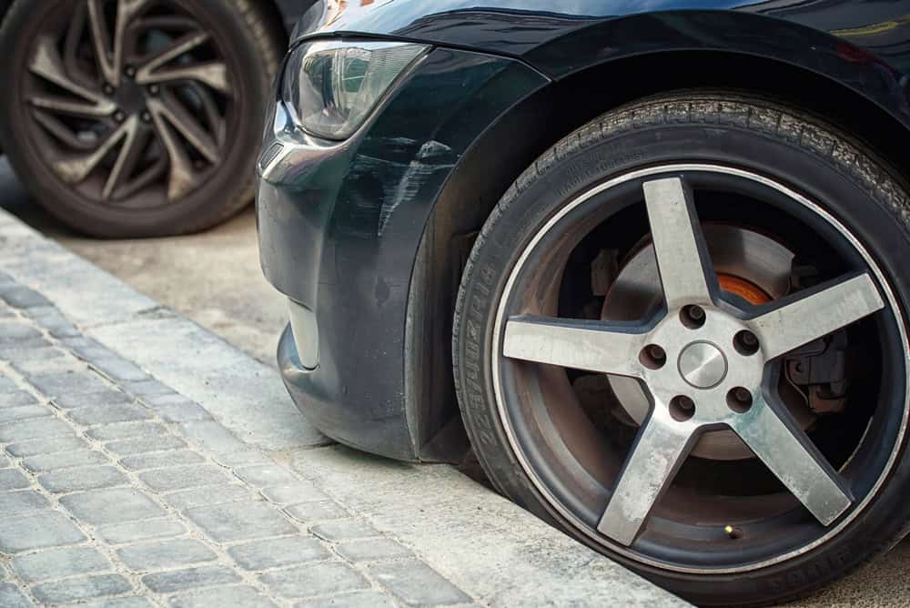 Carro com o pneu encostando no meio-fio