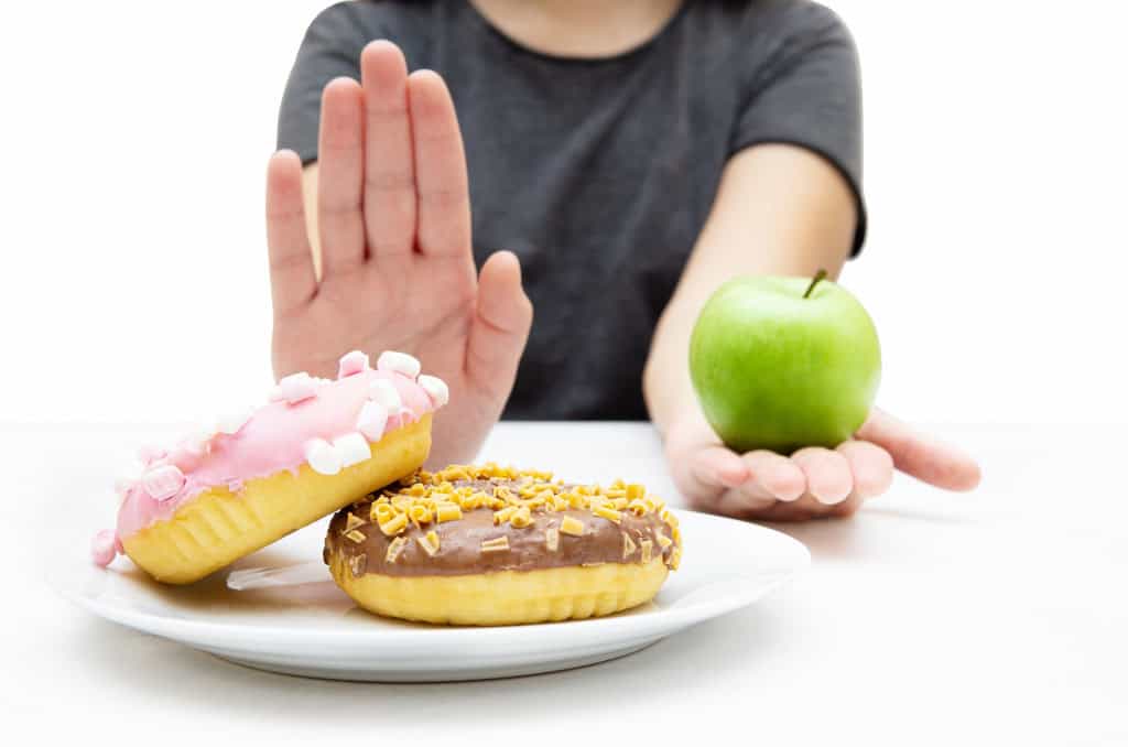 Mulher escolhe uma maçã ao invés de donuts